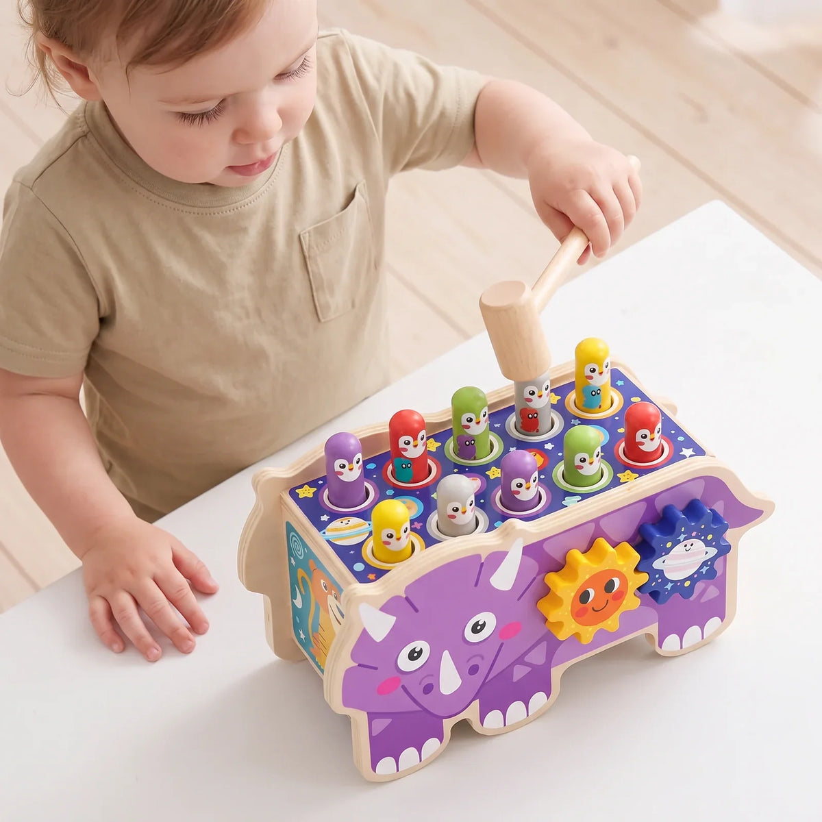 Un enfant debout à une petite table, le maillet levé au-dessus du banc