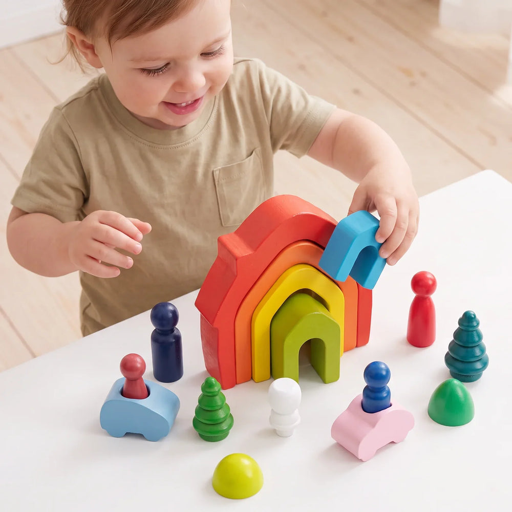 Un enfant debout à une petite table emboîte la maison bleue dans les autres