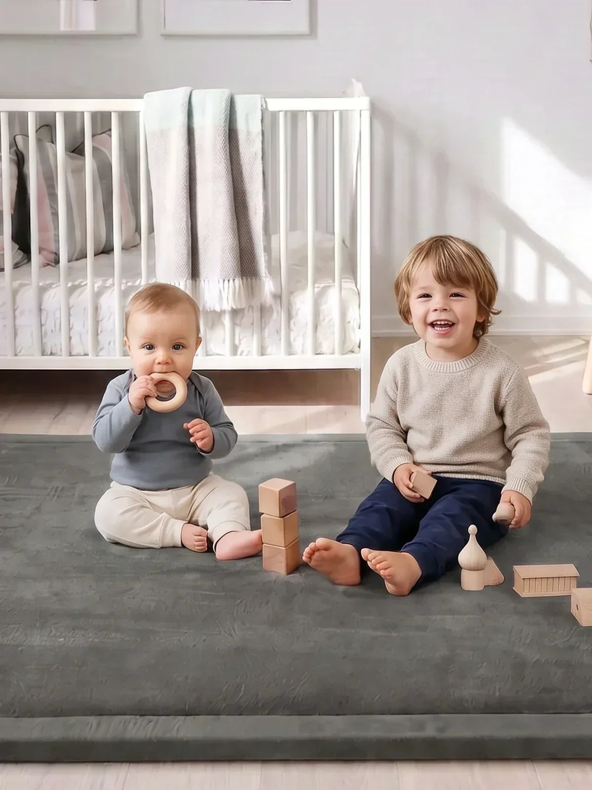 Deux enfants assis côte à côte sur le tapis d'éveil avec des blocs en bois