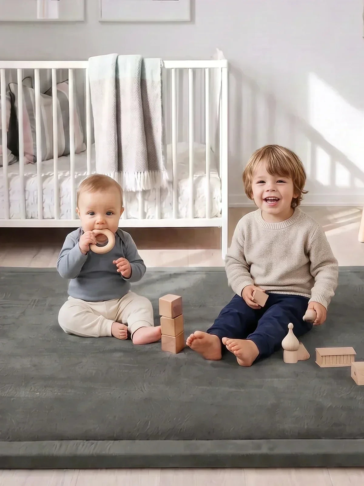 Deux enfants assis côte à côte sur le tapis d'éveil avec des blocs en bois