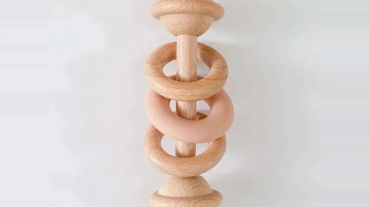 Hochet en bois de hêtre tourné, deux anneaux en bois et un anneau en silicone pêche enfilés sur le manche