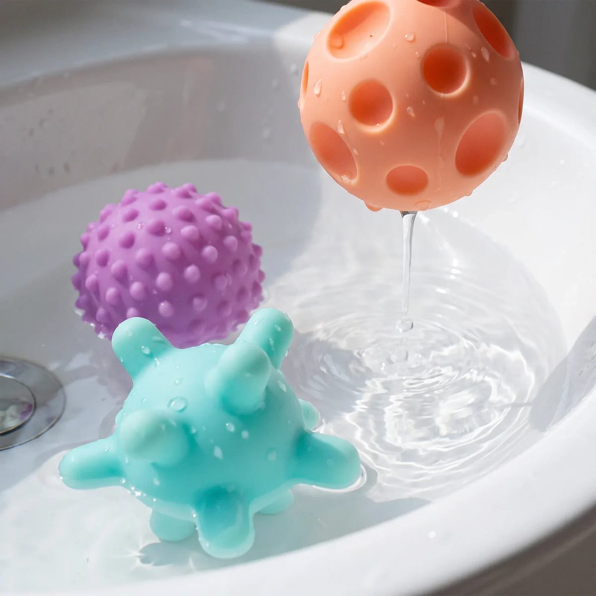 Trois balles dans l'eau, l'une laisse couler un filet d'eau par son trou