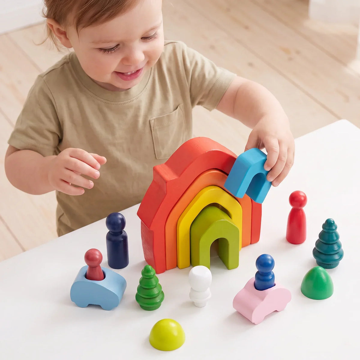 Un enfant debout à une petite table emboîte la maison bleue dans les autres