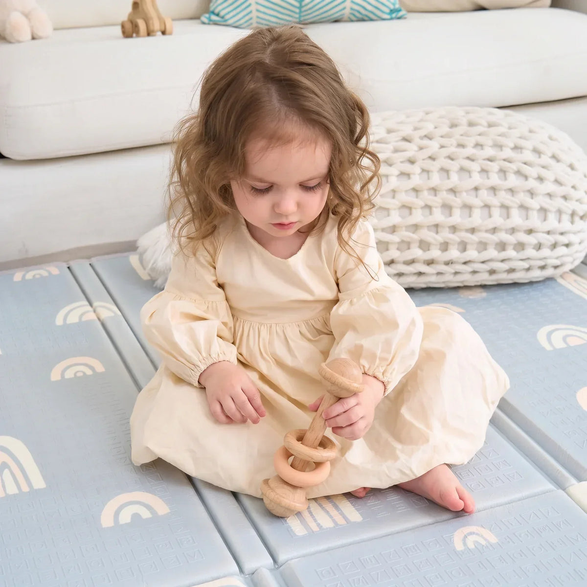 Un enfant tient le hochet à anneaux de hêtre et de silicone