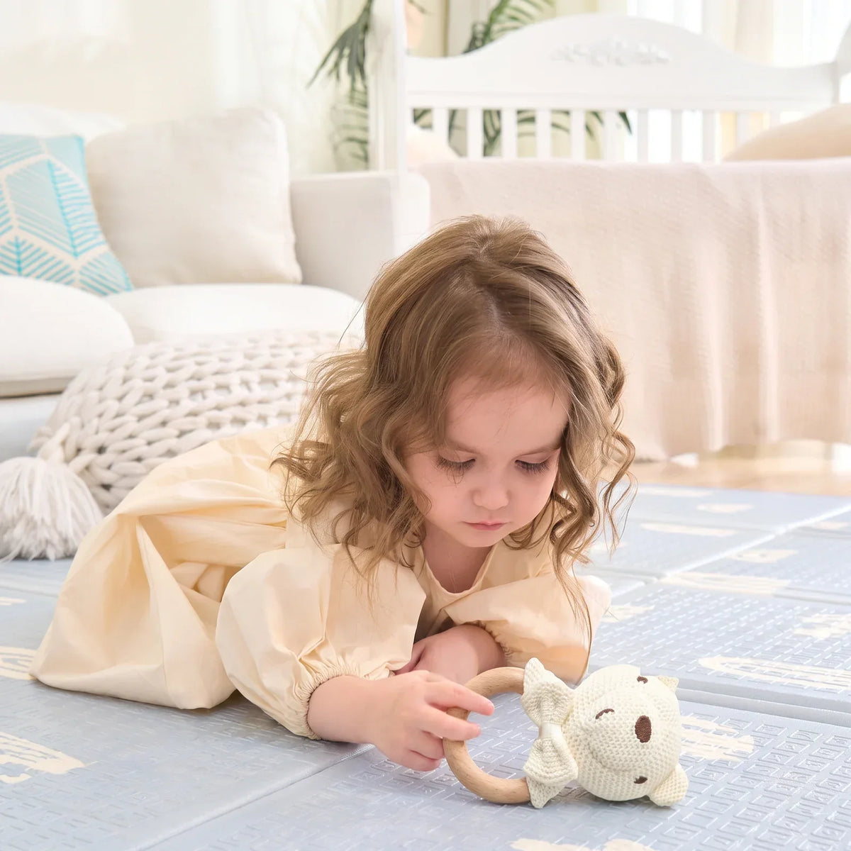Un enfant tient le hochet crochet par son anneau en bois