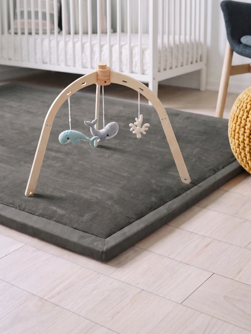 Arche d'éveil en bois, dôme posée sur le tapis d'éveil gris, jouets en feutrine suspendus