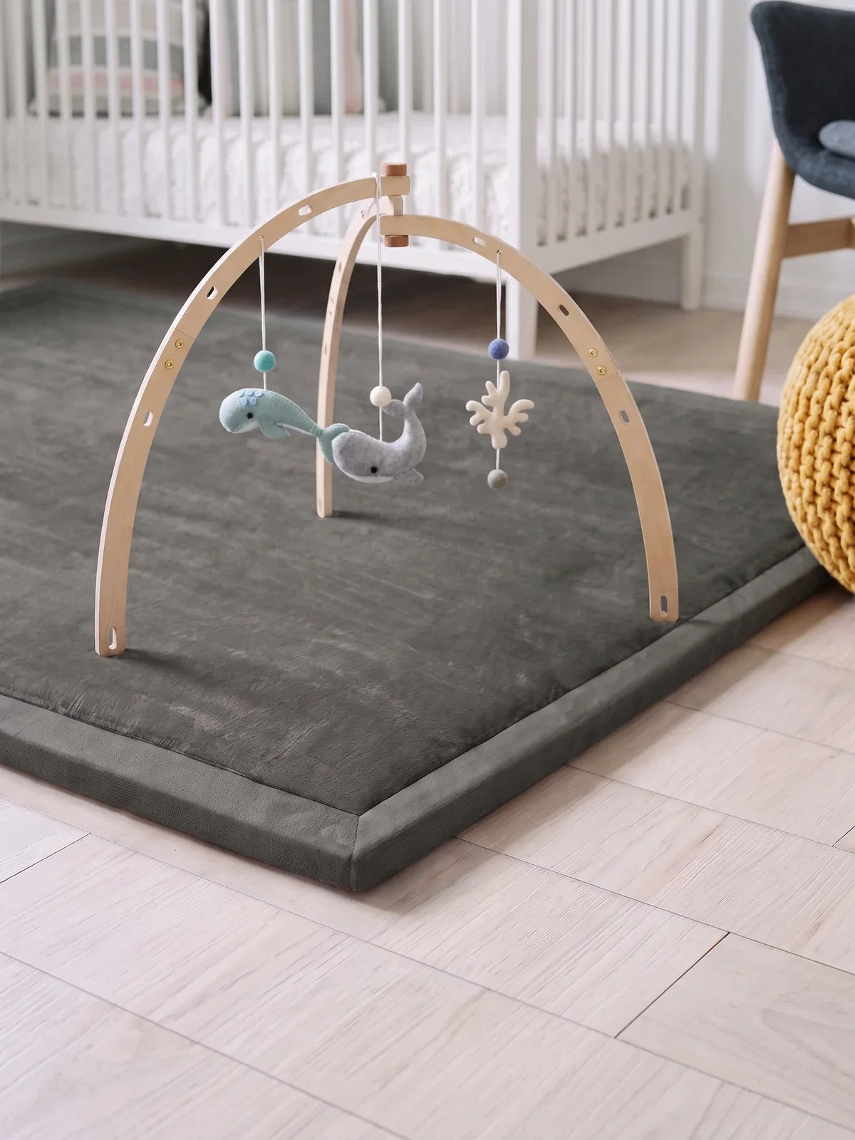 Arche d'éveil en bois, double arc posée sur le tapis d'éveil gris, jouets en feutrine suspendus