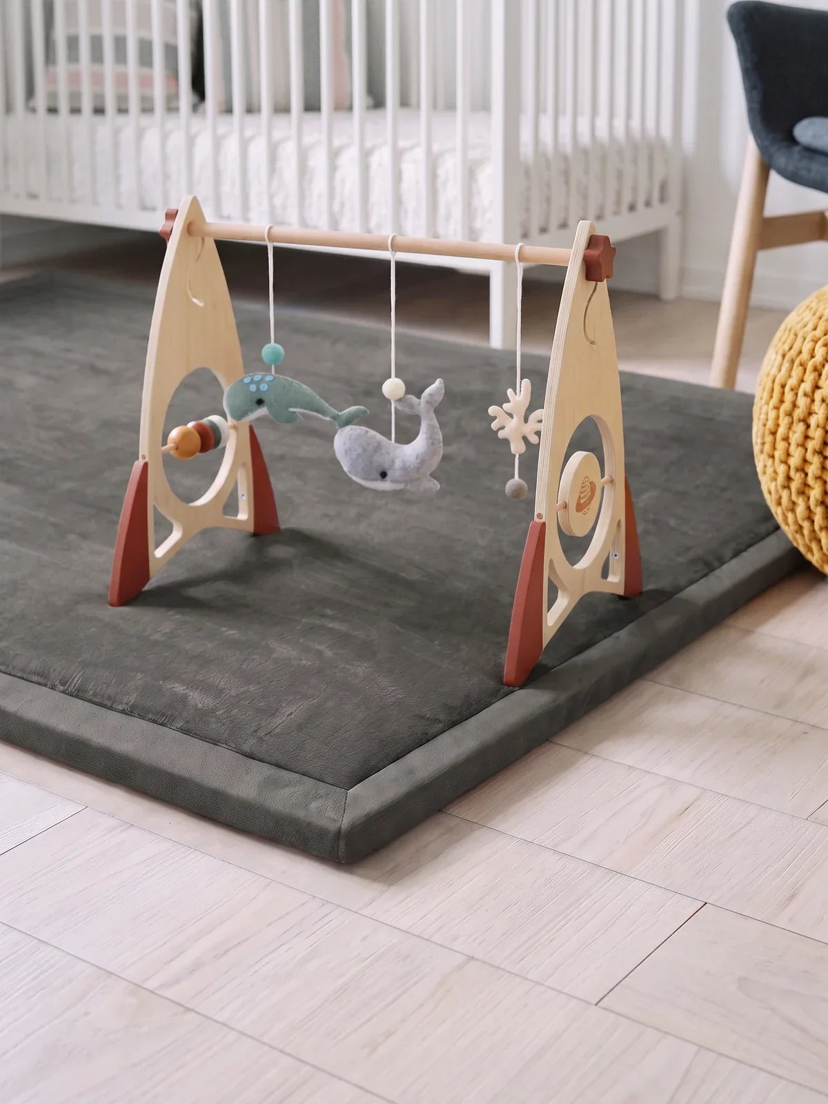 Arche d'éveil en bois, fusée posée sur le tapis d'éveil gris, jouets en feutrine suspendus