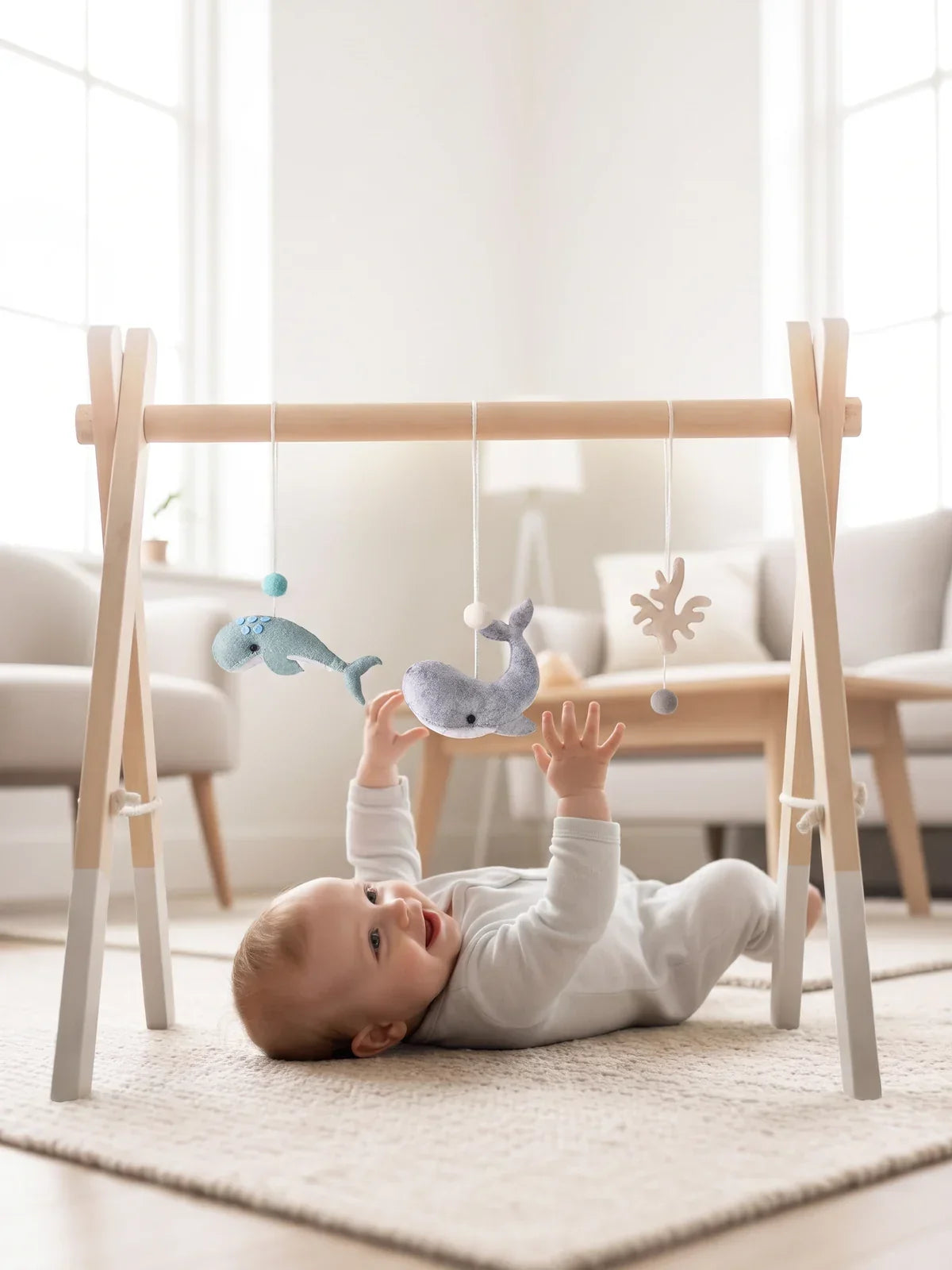 Bébé allongé sur le dos sous l'arche d'éveil, dans un salon