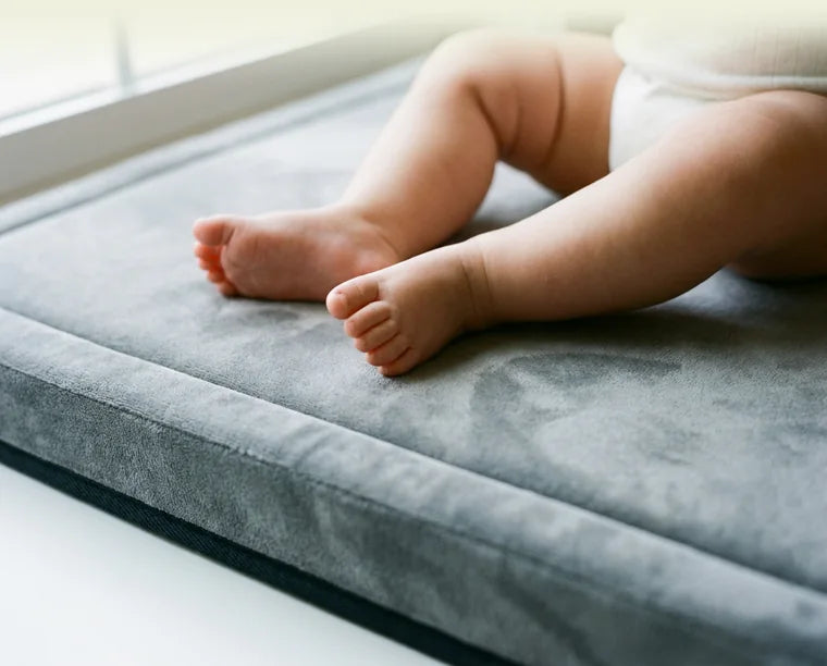 Pieds nus d'un bébé posés sur la surface lisse du tapis
