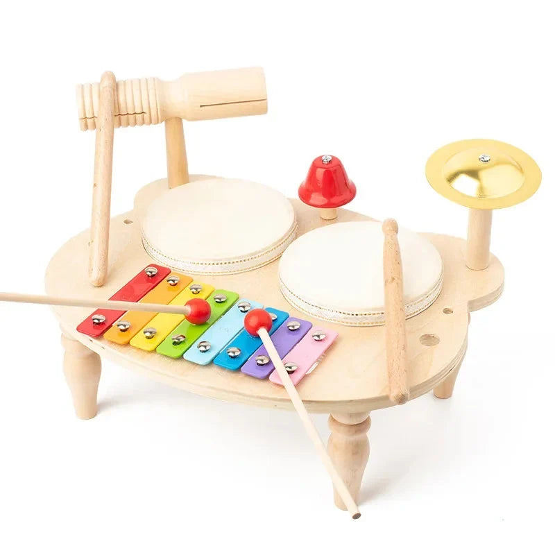 Table musicale en bois : deux tambours, un xylophone, une cloche, une cymbale et un guiro