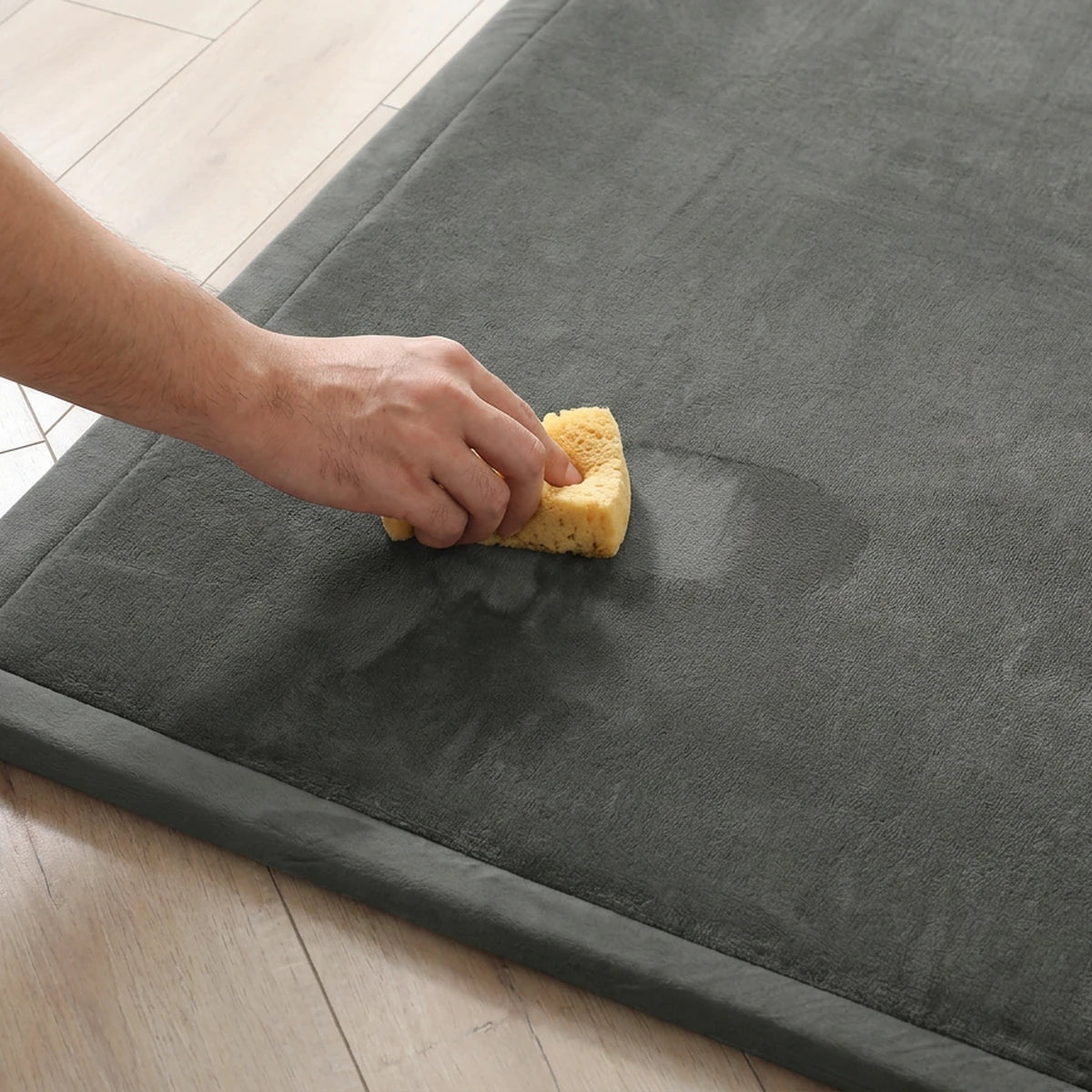 Une main passe une éponge humide sur le velours du tapis